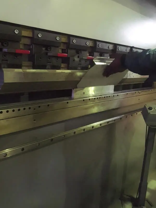 A folded steel canopy part being lifted off the press brake